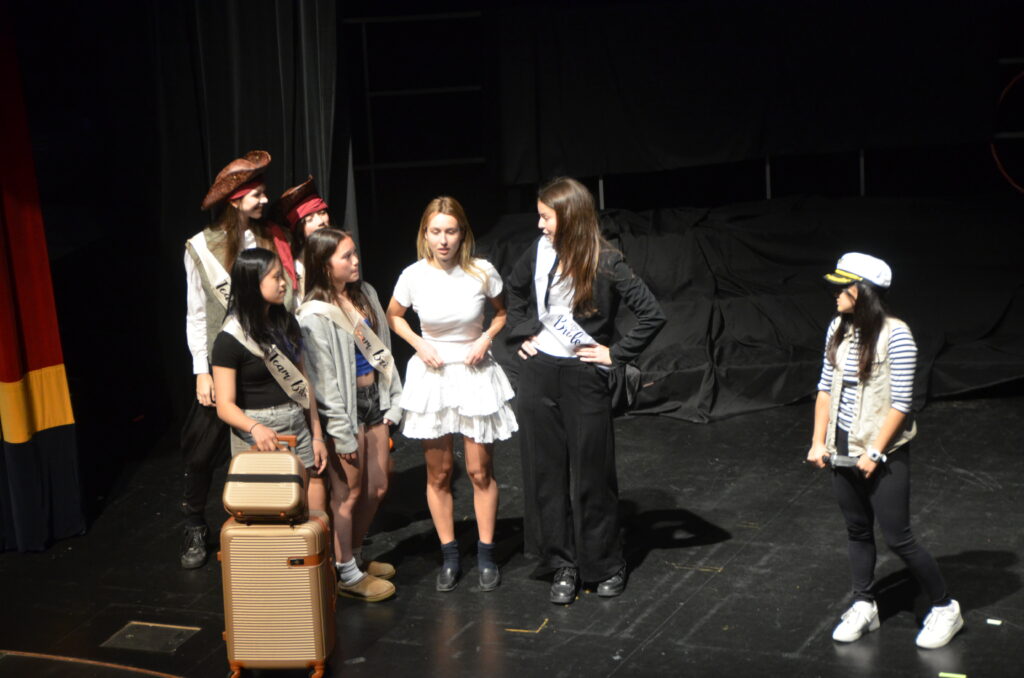 A group of female students in costume on stage.