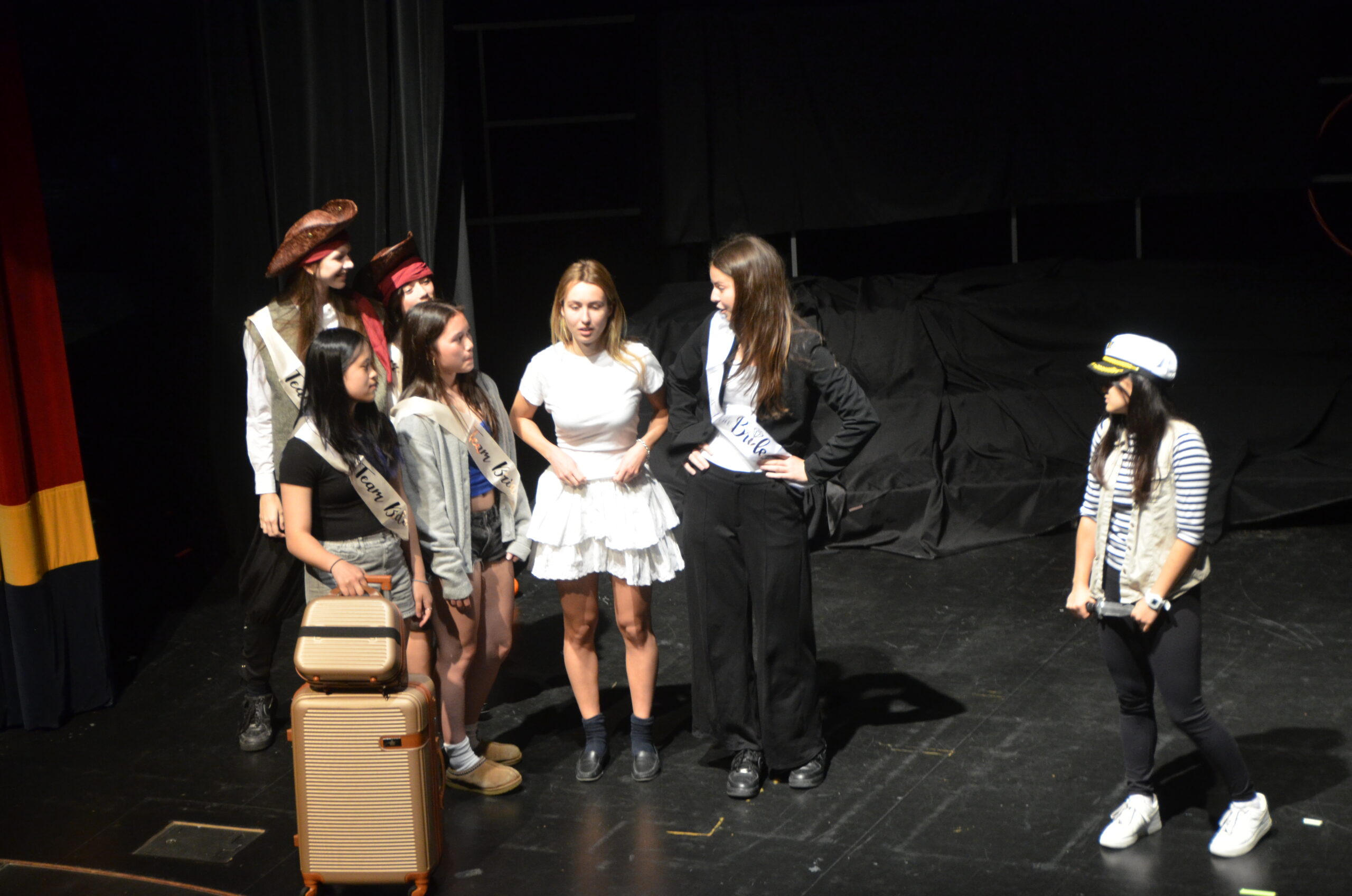 A group of female students in costume on stage.